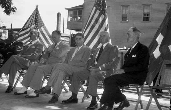 Five men on the speaker's stand at the New Glarus Centennial celebration. From the left are: Gilbert Hoesly, Mayor of New Glarus; Ulrich R. Beusch, Swiss Vice Council from Chicago; Rep. Lawrence H. Smith (R-Racine); and State Senator Melvin J. Olson, (R-South Wayne); State Senator Robert P. Robinson, (R-Beloit); and Rep. Harry A. Keegan, (R-Monroe).