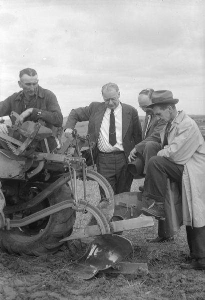 Art Giese, Loganville, and state soil conservation committee members, Ben Rusy, Madison; M.H. Ward, Durand; and Paul Weis, Waunakee, inspecting a two-way plow at the terrace plowing demonstration on the Carl Ribbke farm near Ableman.