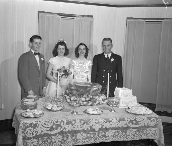 A wedding party at the refreshment table. Included are: best man, William Kessenich; brides attendant, Joan Kessenich; bride, Phyllis Ann Kessenich; Groom, Henry V. Anderson.