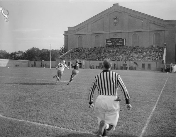Wisconsin - Purdue Football Game at Camp Randall stadium, showing Wisconsin player, Jack Mead, number 51, being pursued by Bob DeMoss, number 50. The University of Wisconsin-Madison Field House is seen in the background. Wisconsin lost 13 to 7.
