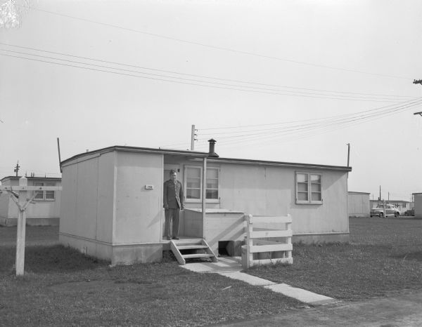 A house at the Baraboo Hercules Powder Plant with Corporal Robert Benson standing in the doorway. He brought his wife from Florida to live here with her son. She is now facing bigamy charges.