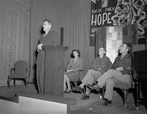Professor Walter Agard addressing an all-campus rally on the Palestine question held at the Memorial Union. Seated left to right: Elaine Sermopskie, Topeka, Kansas, student and chairman of the rally, and Maurice Shudofsky, instructor of Hebrew and English, and Chaplain C. Angel.