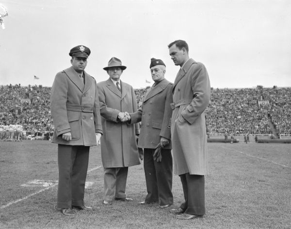 Mayor F. Halsey Kraege and Col. Willis Matthews welcome home two Badger football players, former Lt. Mark H. Hoskins and Col. W.F. Dalton.  Hoskins was a POW in Germany, and Dalton a POW in Japan.  The ceremony took place during the half-time of the Wisconsin-Marquette football game.