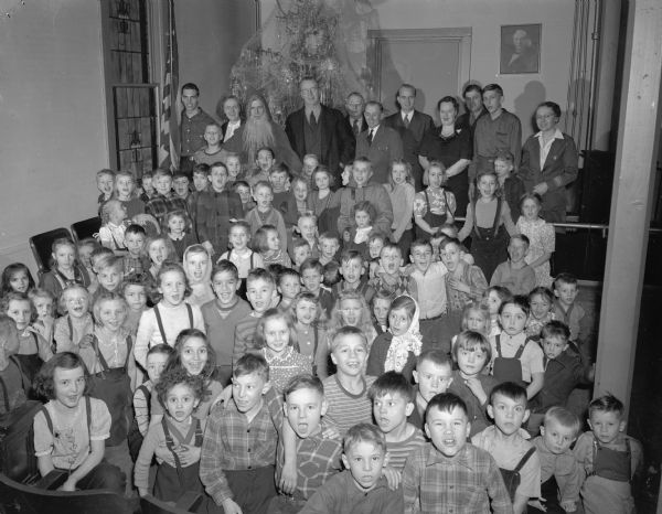 Group portrait of Volunteers of America Christmas Party including Roundy Coughlin and children.  (Roundy's Fun Fund Club?) 
Santa is in the back row with a Christmas tree.