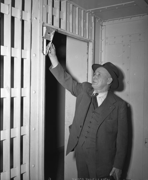Dane County Sheriff John R. Arnold examining the door frame of a cell in the Dane County Jail. Prisoners had attempted to pry open the door in an unsuccessful escape attempt. It was the second such effort in one week.