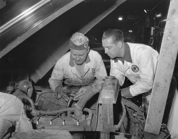Herb Pierstorff, mechanic, shown on the left with Merlin Loe, apprentice mechanic, recently discharged veteran of the Armed Forces, at Waters Motor Company, 802 East Washington Avenue.