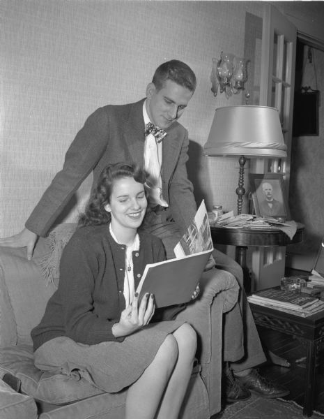 Signe and Peder Sletteland, daughter and son of Mr. and Mrs. Perry A. Sletteland, 2150 Chadbourne Avenue, looking at a catalog. She is a student at Skidmore College. He is home on convalescent furlough from military service.