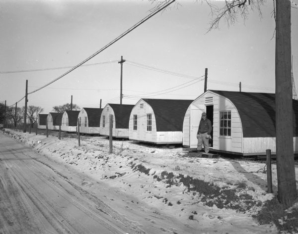 Exterior view of seven buildings of Klinke Hatchery, 3255 Monona Drive, with unidentified man in doorway of one building.