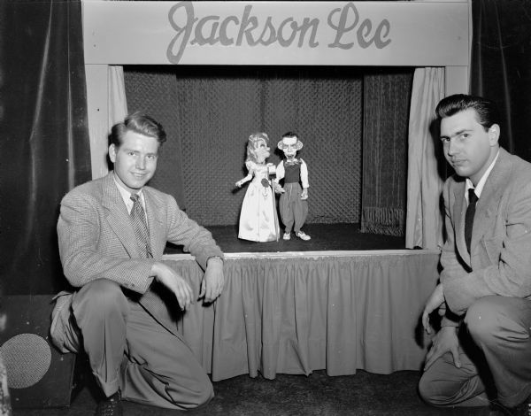 Two men kneeling in front of a marionette show stage with two marionettes on stage. The heading over the stage reads "Jackson Lee."
