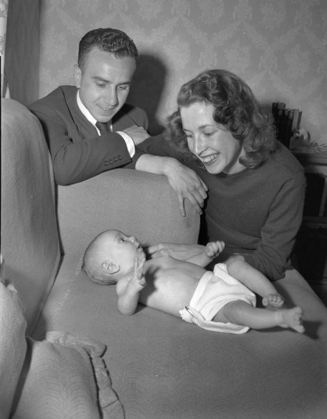 Mr. and Mrs. James Melli, King and Queen of the University of Wisconsin-Madison senior ball, look at their three month old son, James Junior, as they ponder the problem of finding a baby sitter. James (Corrigan) Melli Junior was designated the Crown Prince of the senior ball.