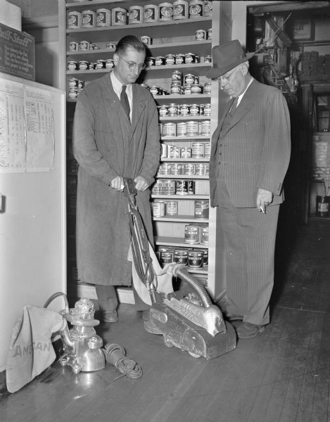 "Art" Schiller, employee of the Fred L. Statz Paint Company, 123 West Main Street, demonstrating the mechanical operation of a floor sander machine to a prospective customer.