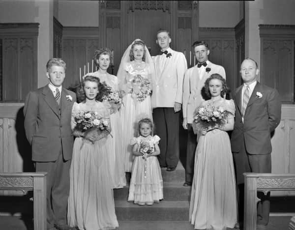 Group portrait of the Brunsell-Skuldt wedding party at Bethel Lutheran Church, 318 Wisconsin Avenue. The bride is Lola J. Skuldt, daughter of Mr. and Mrs. Glen Skuldt, 705 Gilmore Street, and the groom is William R. Brunsell, Jr., son of Mr. and Mrs. William Brunsell, 3821 Paunack Avenue. The wedding party included, in addition to the bride and groom's parents, Jean Toepfer, Esther and Barbara Brunsell, bridesmaids; Betty Jo Thompson, flower girl; and Rollo and John Brunsell, Jr., and Keith Loder, groomsmen.