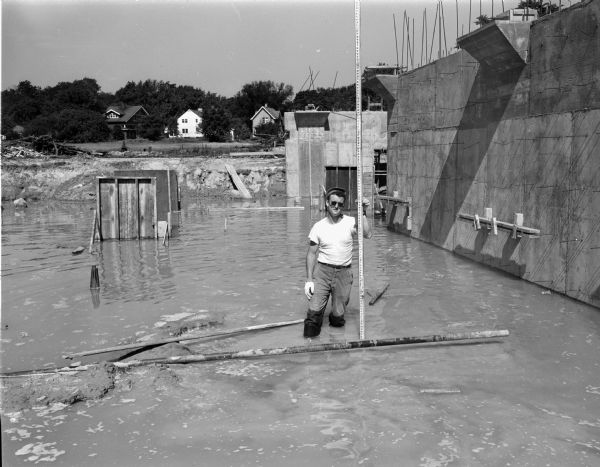 Man standing in flood water at the building under construction for Forsberg Paper Box Company, 2107 Fordem Avenue.