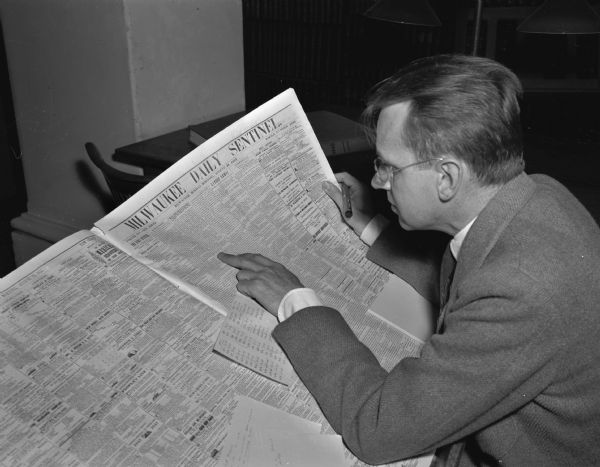 W.H. Glover, University of Wisconsin assistant professor in agricultural economics, reading an edition of the "Milwaukee Daily Sentinel" in the Wisconsin State Historical library. Glover is writing a history of 100 years in Wisconsin agriculture.