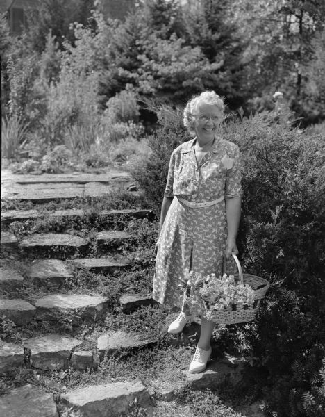 Mrs. Walter (Genevieve) Dakin, 4110 Mandan Crescent, Nakoma, in her garden. Mrs. Dakin had just finished her term of office as president of the Wisconsin Federated Garden Clubs.