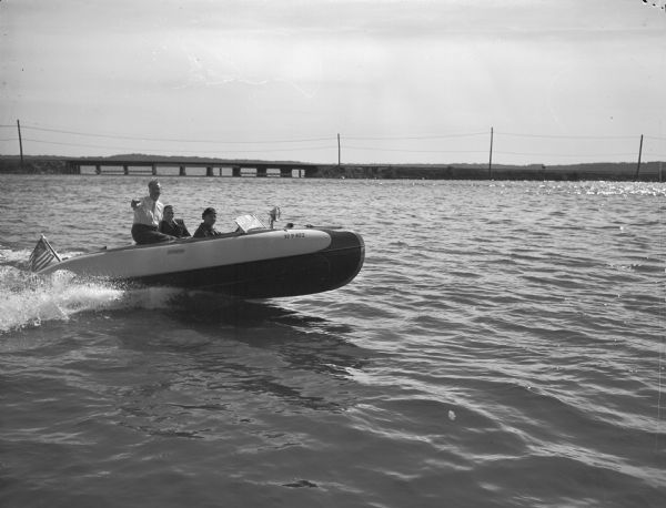 Joseph L. "Roundy" Coughlin, sports writer for the "Wisconsin State Journal," and two other men in a Larson Falls Flyer motorboat on a lake.