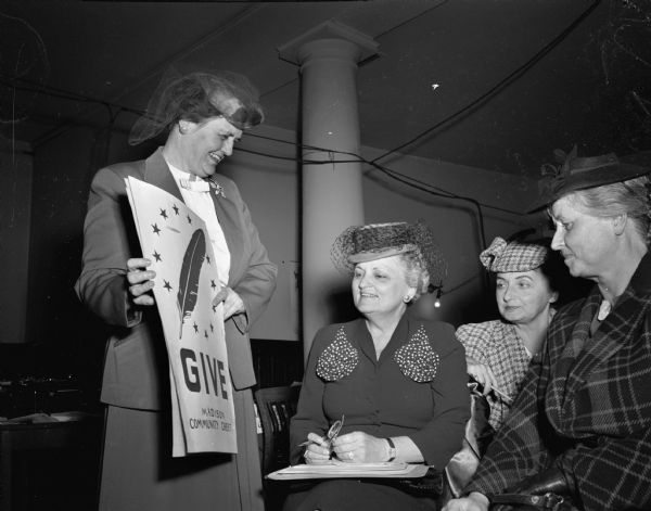 Four women preparing to conduct the annual Community Chest "Red Feather" campaign. The woman in houndstooth check hat and suit is Mrs. William (Catherine) Reck, 1 East Gilman Street, chairman of Ward 11.