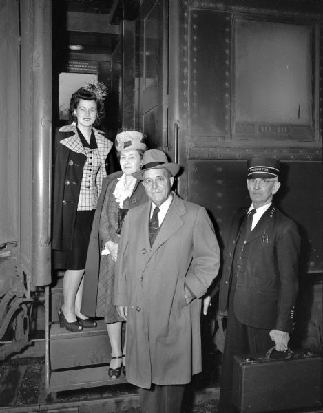 Betty Gene Gardner, Ridgeway, who was chosen Queen of America's Dairyland at the 1946 Wisconsin State Fair, is shown boarding a train for the Dairy Industries Exposition in Atlantic City where she will represent Wisconsin's dairy industry. Her escorts are Mr. & Mrs. E.K. Slater of Milwaukee. The train conductor is shown holding her suitcase.