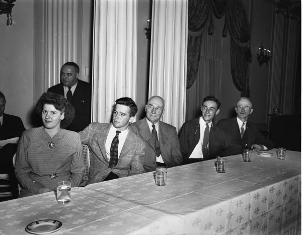 Three grand champion winners are shown at the Junior Livestock Exposition Banquet in the Loraine Hotel. Seated left to right are: Dorothy Disch, Evansville, winner of the grand championship of the show in sheep classes; Harry May, Mineral Point, winner of the grand championship of the show in the beef classes; John Scott Earll, Prairie du Chien, prominent shorthorn breeder; Vernon Miller, Lodi, winner of the grand championship of the show in the swine classes; N.H. May, Mineral Point, Aberdeen Angus breeder and father of Harry.