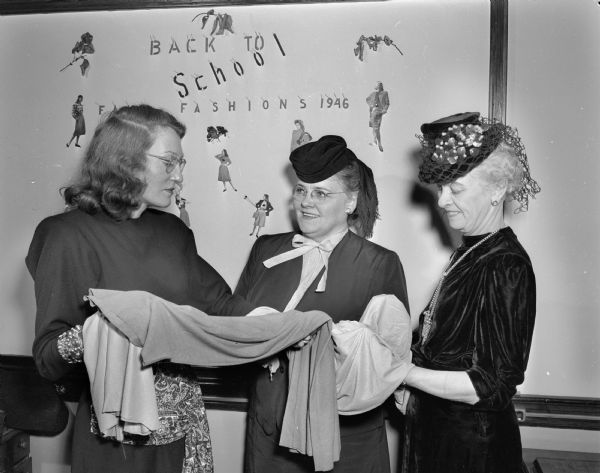 Three women in the millinery class at the Madison Vocational School looking at fabrics. Left to right: Mrs. Martelle Swanson, class instructor, and students, Mrs. J.A. (Vangel) James, Mrs. Elmer E. (Anna) Barlow.