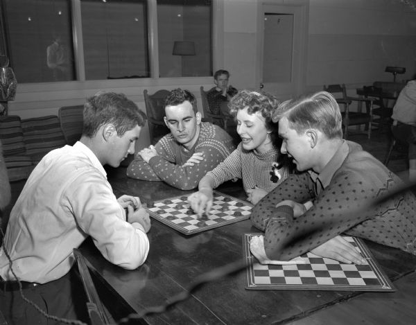 Playing checkers at the LOFT's New Year's party in the Community Center are, (left to right) David Rendall, Joan Scheiwe, watching are Tom Roth, and Gordon Anderson.