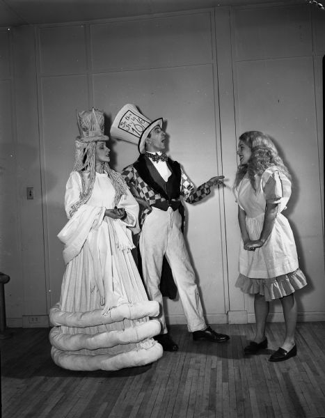 Group portrait of cast members of the Madison Theater Guild's presentation of "Alice in Wonderland," dressed in costume. Left to right: Mrs. D.D. (Lucille) Dunn, 222 Lakewood Boulevard, dressed as the Queen; J. Stanhope Edwards, 503 State Street, dressed as the Mad Hatter; and Marilyn Eddy, 134 West Wilson Street, dressed as Alice.
