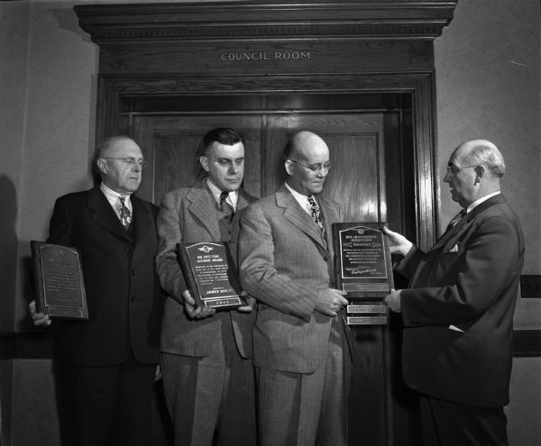 R.E. Gess, district engineer with Employers Mutual Insurance Company, presenting safety awards to three employees of James Manufacturing Company, Fort Atkinson.  Left to right: W.J. Wandschneider, supervisor of Plant 3; W.L. Dahms, supervisor of Plant 1; and R.G. Davis, personnel director of the company.