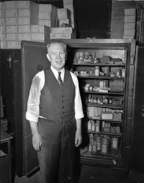 Emil A. Hayden, treasurer-manager of the Madison Drug Company, 654 Williamson Street, shown in the company storeroom where he had been bound and gagged by four armed bandits who had looted a thousand dollars worth of morphine-type narcotics.