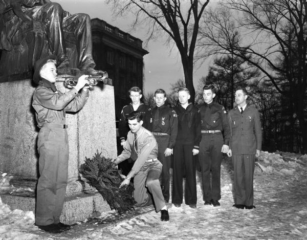 Madison Boy Scouts and their leader pay tribute to Abraham Lincoln on his birthday by placing a wreath at the foot of the statue on Bascom Hill. Dick Feldt is playing the bugle, B. . Harks is placing the wreath, watching are Bob Grant, George Stebbins, Peter Van Wagenen, Russ Gordon, and Gunn Smith, assistant Scout executive of the Four Lakes Council.