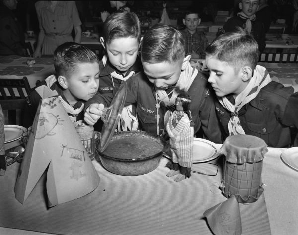 Four Cub Scouts inspecting a hot dish at the first "Blue and Gold" Cub Scout banquet for Pack 302 at Randall School, 10 North Spooner Street. Left to right: Dean Weidmann, son of Mr. and Mrs. Andrew Weidmann, 1719 Chadbourne Avenue; Tommy Alberti, son of Mr. and Mrs. Thomas Alberti, 1724 Van Hise Avenue; Howard Holzworth , son of Mr. and Mrs. Howard Holzworth, 1546 Jefferson Street, and Kenneth Thompson, son of Mr. and Mrs. K.P. Thompson, 1810 West Lawn Avenue.