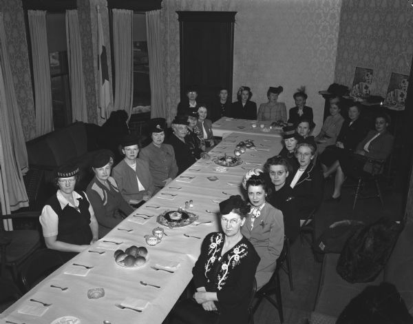 Twenty-one women, chairmen of collections for the 1947 Red Cross fund campaign in Madison wards and suburbs, seated around a luncheon table, after working out their campaigns at a conference.