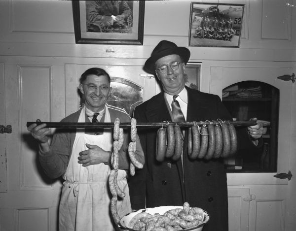 Joseph L. "Roundy" Coughlin with butcher and strings of sausages.