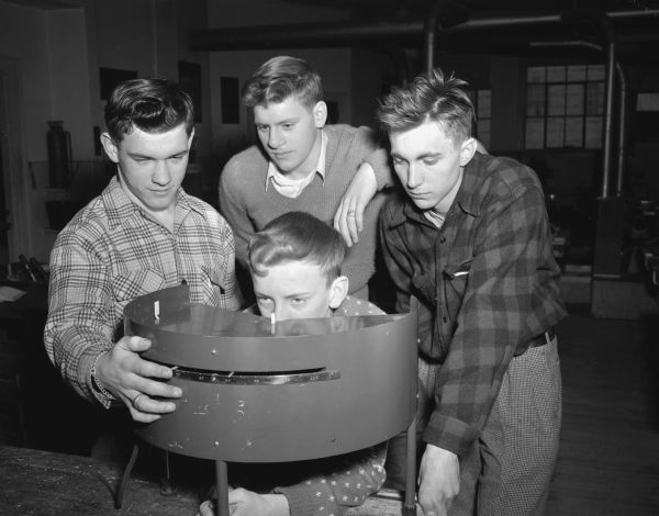 Art Posbeck is checking his field of vision on equipment from the Badger Ordnance Works in a driving class. Watching him are left to right: Dick Gettle, Bob Wise, and Billy Gatz.