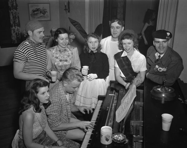 Eight students, in costume, gathered around a piano at a University of Wisconsin-Madison beer party.