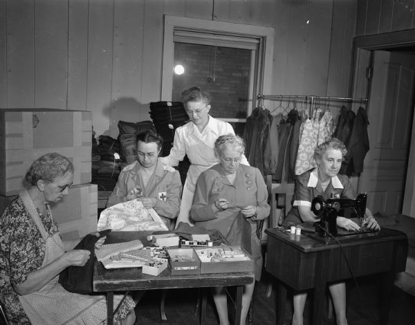 Red Cross volunteers making clothes for destitute children in war torn countries. Left to right:  Emma Henwood, Mrs. Casimir D. (Fredericka) Zdanowicz, Mrs. F.O. (Lucile) Pennington, county production chair for the Red Cross, Mrs. J.V. McKee, Mrs. B.C. (Mae) Ranz.