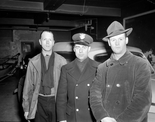 Madison Police Officers (left to right): John Sweeney; Ervin Grahn; and George Cross; pictured at the Madison Police Station garage in front of a bank robber's car.  They captured the armed bandit of the Loganville State Bank earlier in the day after spotting his rented car on West Gorham Street.