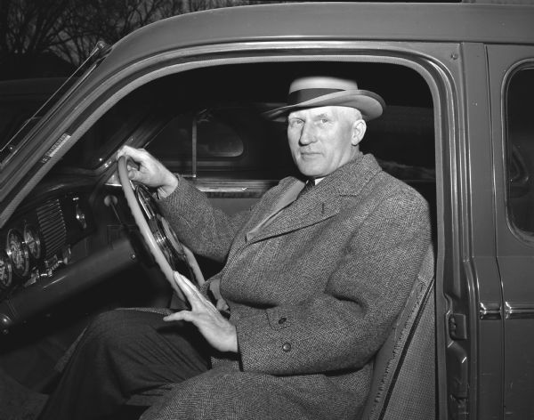 Prof. Gustav Bohstedt, University of Wisconsin Animal Husbandry professor, seated in his automobile.  He was chosen as a courteous driver in the AAA campaign after driving around the Square.