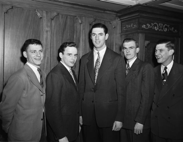 Group portrait of the University of Wisconsin men's basketball team who won the Western Conference Championship.  Left to right: Forwards Bobby Cook and Exner Menzel, Center Ed Mills, and Guards Glen Selbo and Walter Lautenbach. All were ex World War II servicemen.