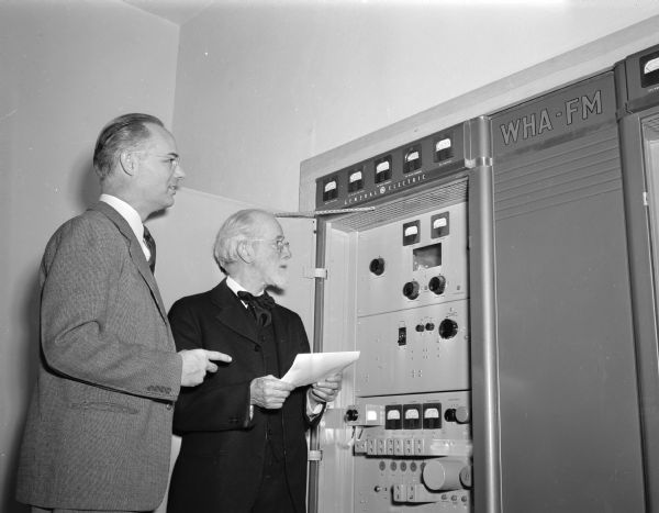 Dr. William H. Lighty, who was around WHA when they were blowing their glass radio tubes, glances over one of the two cabinets which contain the new FM broadcasting equipment. To his left is Station Director, Harold McCarty.