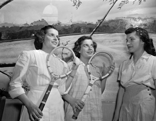 Posing in front of a mural of Madison, three high school girls with tennis rackets symbolize the spirit of "spring fever." From left are Barbara Gilbert, 2716 Milwaukee Street; Lois Cory, 3238 Sherman Avenue; and Lois Cook, 2346 East Mifflin Street.