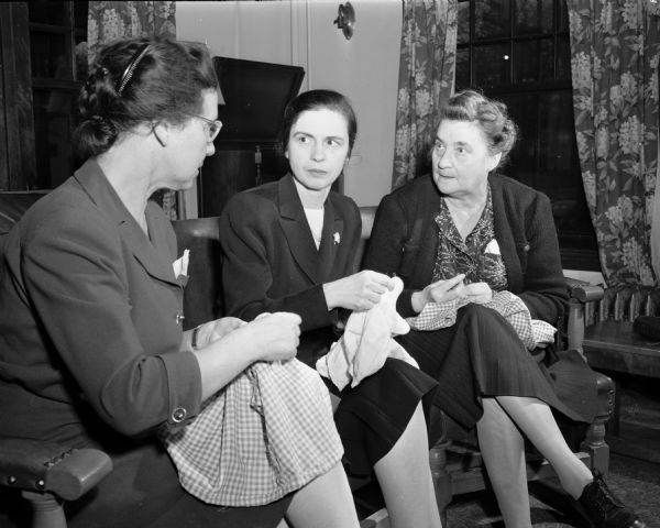 Mrs. Fred R. (Edith) Jones, Mrs. Kenneth H. (Pauline) Parsons, and Mrs. Hans T. (Josephine) Sondergaard, of the Unitarian Service Committee, are shown mending clothing for destitute Spanish refugees in France. Mrs. Parsons is part of a committee selling tickets for a presentation by Ted Allan who traveled as a special correspondent for the Columbia Broadcasting system and visited France where he encountered the refugees.
