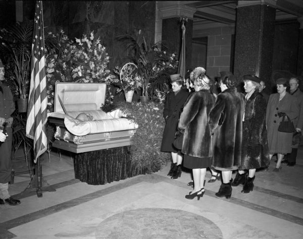 Women executive office employees filing past the casket containing the body of Governor Walter Goodland in the Wisconsin State Capitol.