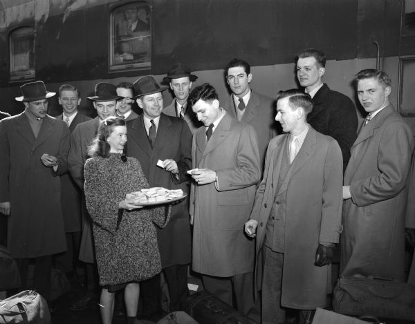 Woman serving cheese to members of the University of Wisconsin championship basketball team members at the train depot before their departure for the NCAA tournament in New York.