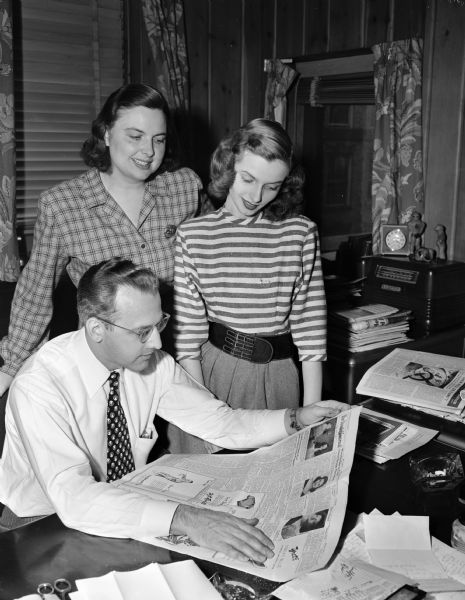 Pictured are Roy Matson, editor of the <i>Wisconsin State Journal</i> (seated), and Louise Marston, society editor of the paper (standing at left), discussing the First Anniversary issue of the Youth Journal column with Nancy Hoffland (standing right), chair of the Youth Council Newspaper Committee.