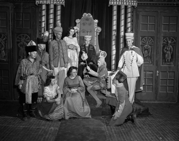 A scene from "The Forest Princ,e, an operetta set in 16th century Russia, which was presented by the East High School a cappella choir and the concert orchestra.  Standing left to right are: Gordon McMahon, Herbert Niebuhr, Gordon R. Rom, Violette Jakovich, Jim Peterson and Chuck Anderson.  Kneeling at the right is Walter Kahn.  Seated are Betty Jenson, Margaret McBoyle, and Ed Kitson.