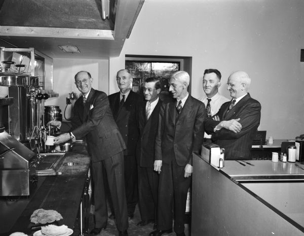 Edward L. Kelly is shown with a group of other restaurant men at the opening of his new coffee shop, 1413 University Avenue.  Left to right: Edward L. Kelly (drawing a cup of coffee), Thomas Lawrence Tuttle, Louis Waldorf, James I. "Cop" Coppernoll, William A. Anderson, and Mark F. Martin. 

For 21 years Ed Kelly and Mike Egan ran the Egan & Kelly Restaurant, 114 N. Fairchild Street. 

For 49 years, Thomas Lawrence Tuttle operated the Columbian Cafe aka the Lunch Wagon, 605 E. Wilson Street.  

For 33 years Louis Waldorf owned Waldorf's Restaurant, 821 University Avenue.

For 20 years James I. Coppernoll owned Cop's Cafe, 11 W. Main Street.

For 20 years William A. Anderson owned Cleveland's Lunch, 410 E. Main Street.

For 22 years Mark F. Martin owned Martin's restaurant, 107 State Street.