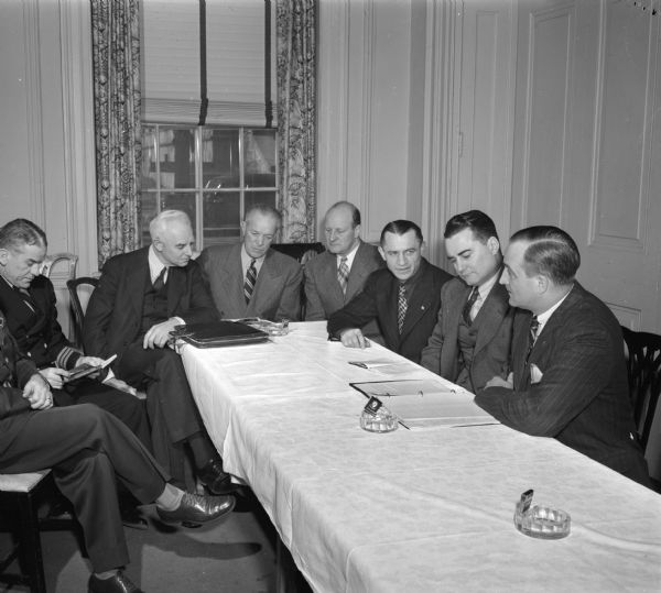 Members of the National Collegiate Athletic Association boxing committee meeting at the Madison Club prior to the national tournament held at the University of Wisconsin-Madison Field House. Left to right are: Col. H.B. Pittsbury, United States Military Academy; Commander John S. Merriman, Jr., United States Coast Guard Academy; Dr. Carl P. Scott, Penn State; I.F. Toomey, California Aggies; Guy Sundt, Wisconsin; DeWitt Portal, San Jose State; Edwin Haislet, Minnesota; and Thomas Carruthers, Virginia.