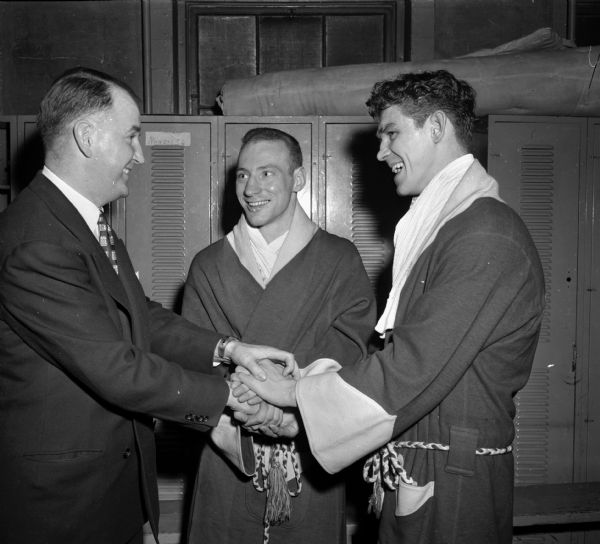 Two college boxers dressed in robes being greeted by a man at the NCAA National Boxing Tournament at the University of Wisconsin-Madison Field House. The name "Nero" is inscribed on the negative.