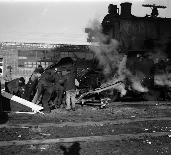 Police and trainmen for the Northwestern Railroad removing the bodies of Mr. and Mrs. William C. Thompson (Alice) from their truck, which collided with a Northwestern passenger train at the Commercial Avenue crossing.