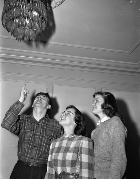Pictured left to right: David Miller; Elaine Schoenoff, West High; and Pat Anderson, East High, members of the Madison Youth Council and committee members of the Junior Red Cross Ball, "Apple Blossom Time," in the Loraine Hotel ballroom where the event will be held on April 12 to raise money for the National Children's fund for the purchase of food and medicine for children in war-torn countries.  A new national fund, made up of tax money from phonograph record sales, has been set aside to pay expenses of bands and orchestras for benefit concerts and dances so that all profits can be turned over to the National Children's Fund.